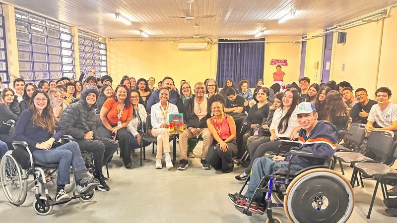 Auditório do Colégio Caldas Jr., com os estudantes reunidos em torno de Rubens Rufino, filho de Léila Gonzalez