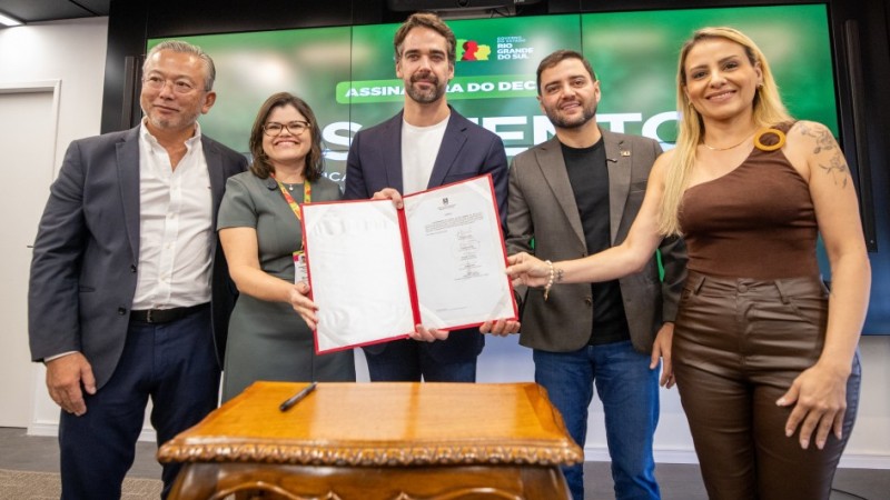 Lan&ccedil;amento da Pol&iacute;tica Integrada de Gest&atilde;o do Ambiente Escolar. Autoridades presentes seguram o documento com a pol&iacute;tica.

