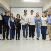 Registro coletivo em ambiente interno, com um grupo alinhado lado a lado para foto institucional. O governador ao centro segura um documento, indicando ato formal de entrega.