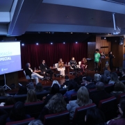 Audit&oacute;rio com plateia assistindo a uma mesa de debate sobre educa&ccedil;&atilde;o especial. No palco, cinco participantes conversam diante de uma tela que exibe o Guia da Educa&ccedil;&atilde;o Especial na Perspectiva Inclusiva da Rede Estadual de Ensino. H&aacute; int&eacute;rprete de Libras e p&uacute;blico atento.